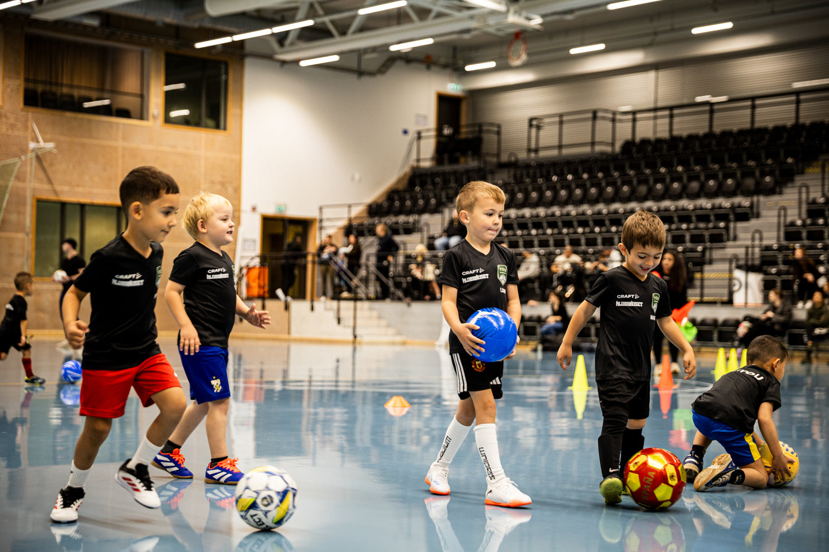 Children playing with soccer balls in an indoor sports facility.