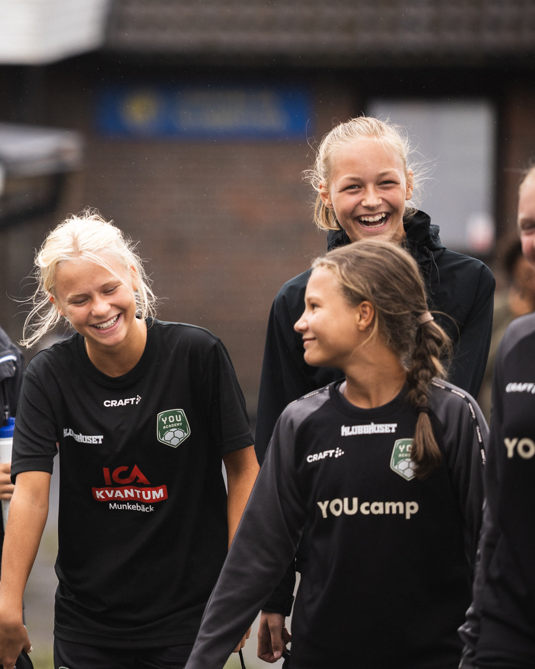 Three people wearing black shirts with visible branding walking together.